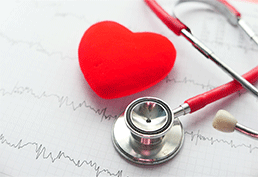 Stethoscope next to a red heart on an EKG print out.  