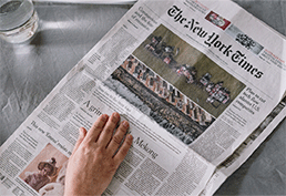 hand on an open New York Times newspaper.