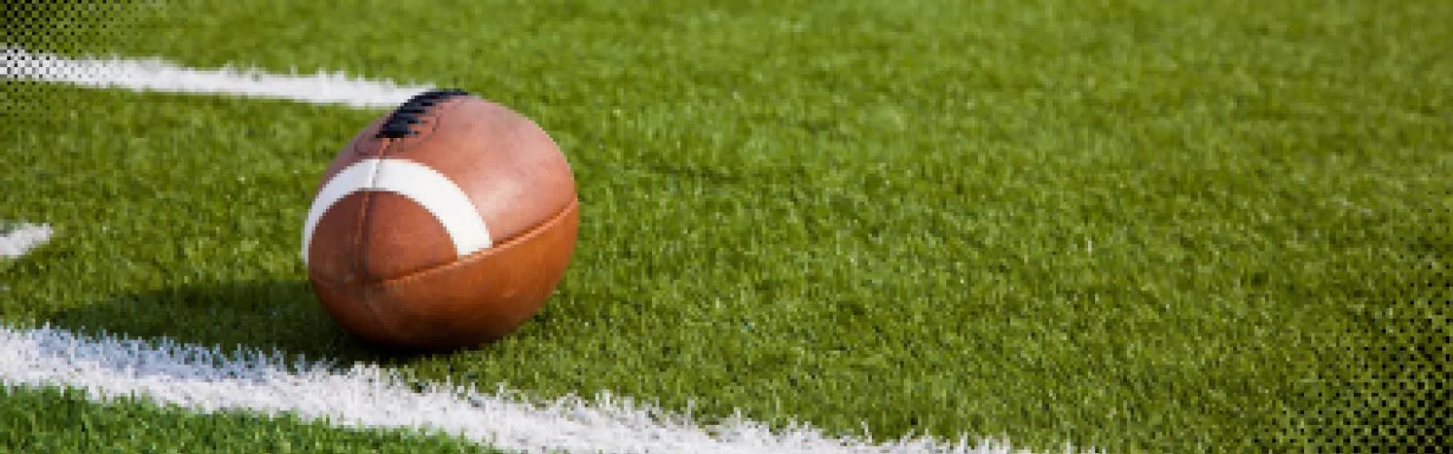 A football lined up on a yard line of a football field. 